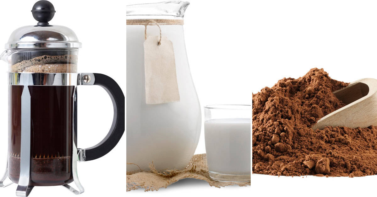A French press with coffee, a glass jug with milk beside a glass of milk, and a pile of cocoa powder with a wooden scoop await transformation into a delightful Mocha Latte.