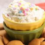 A bowl of funfetti dessert dip with sprinkles, served with cookie wafers.
