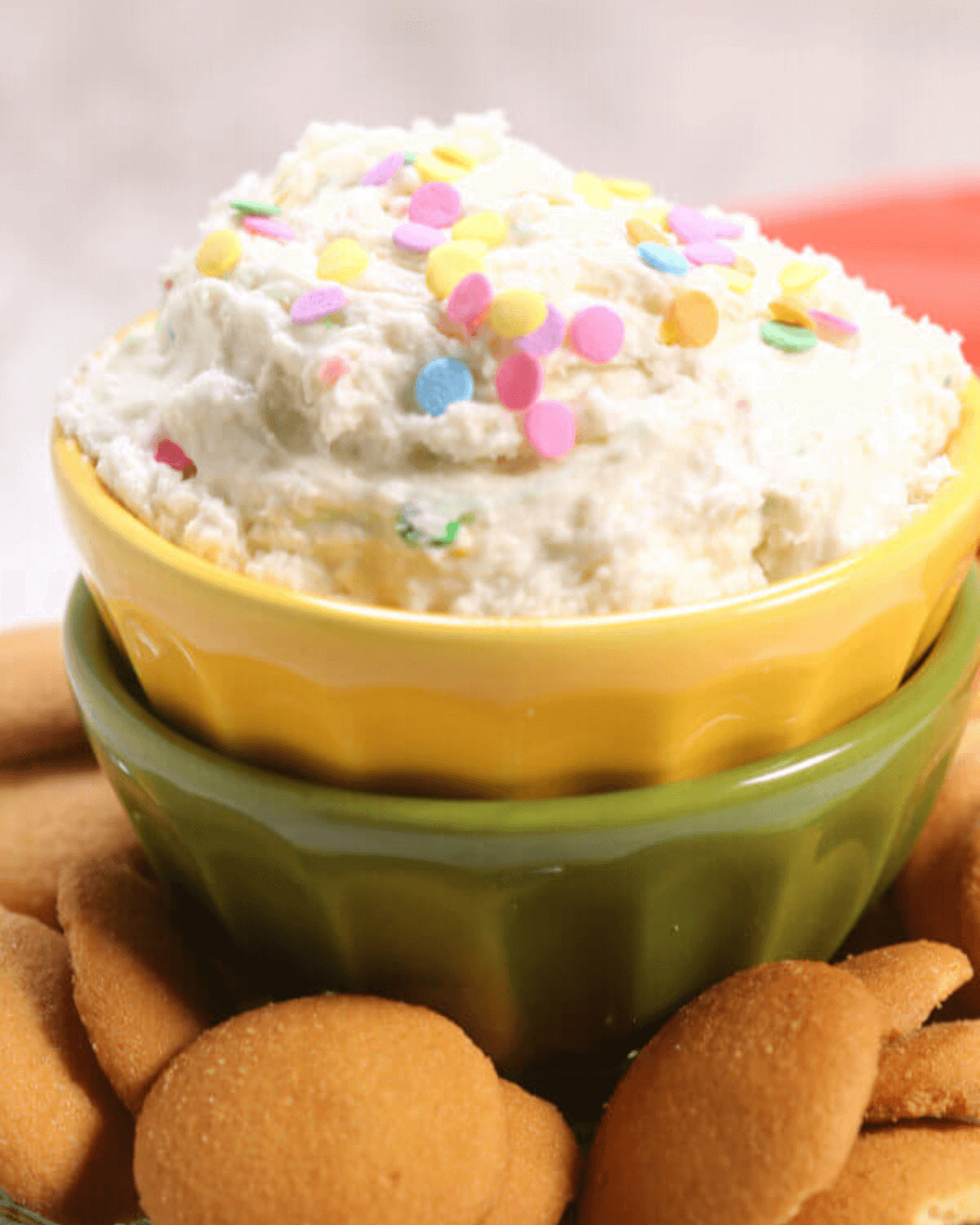 A bowl of funfetti dessert dip with sprinkles, served with cookie wafers.