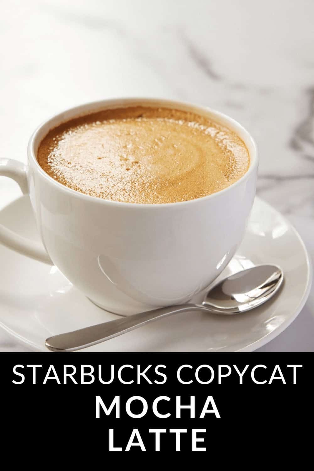 A white cup brimming with a rich Mocha Latte rests on a saucer beside a spoon, elegantly arranged on the marble surface. At the bottom, the text reads, "Starbucks Copycat Mocha Latte.