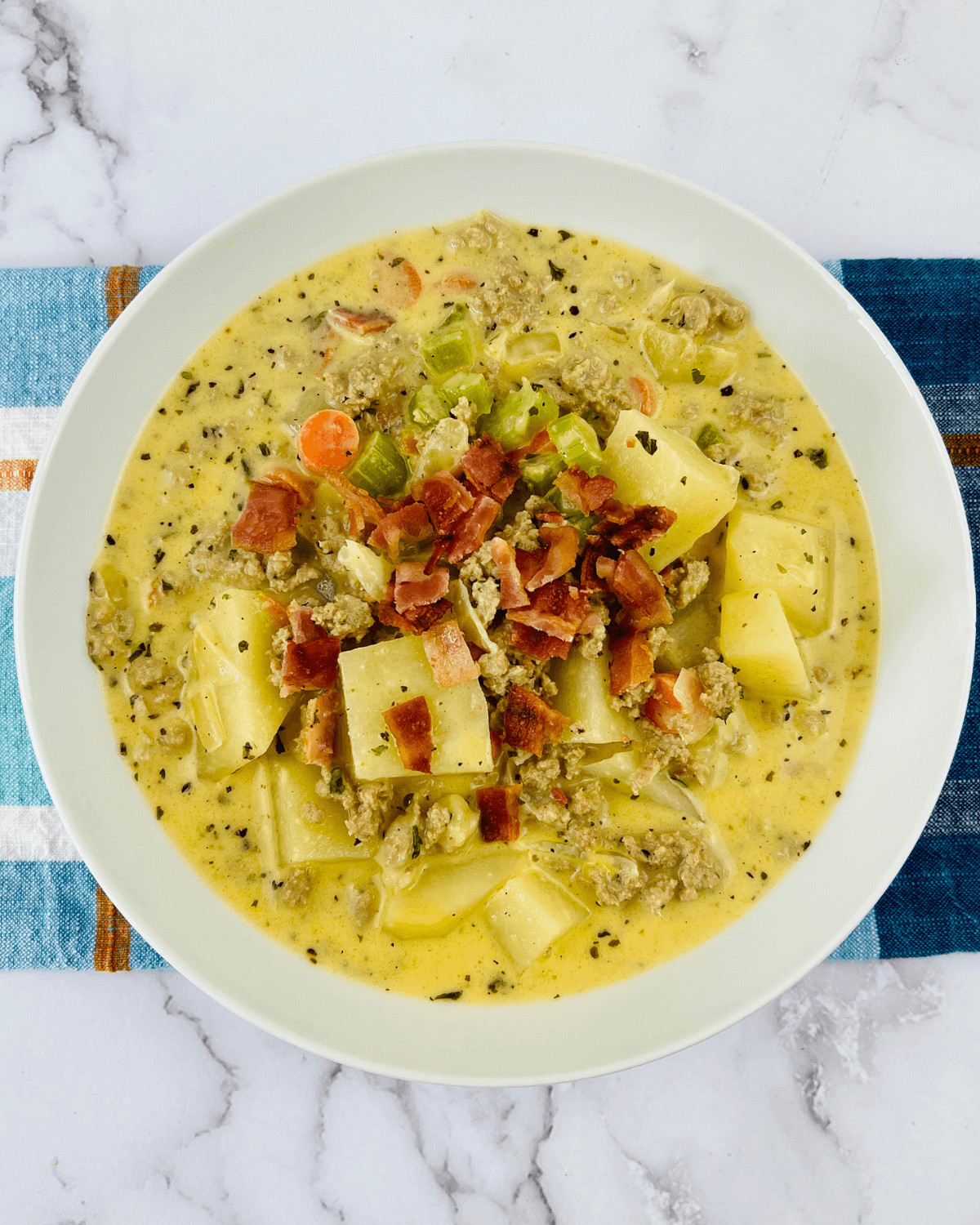 A bowl of soup with potatoes and bacon, also known as Bacon cheeseburger Potato Soup.