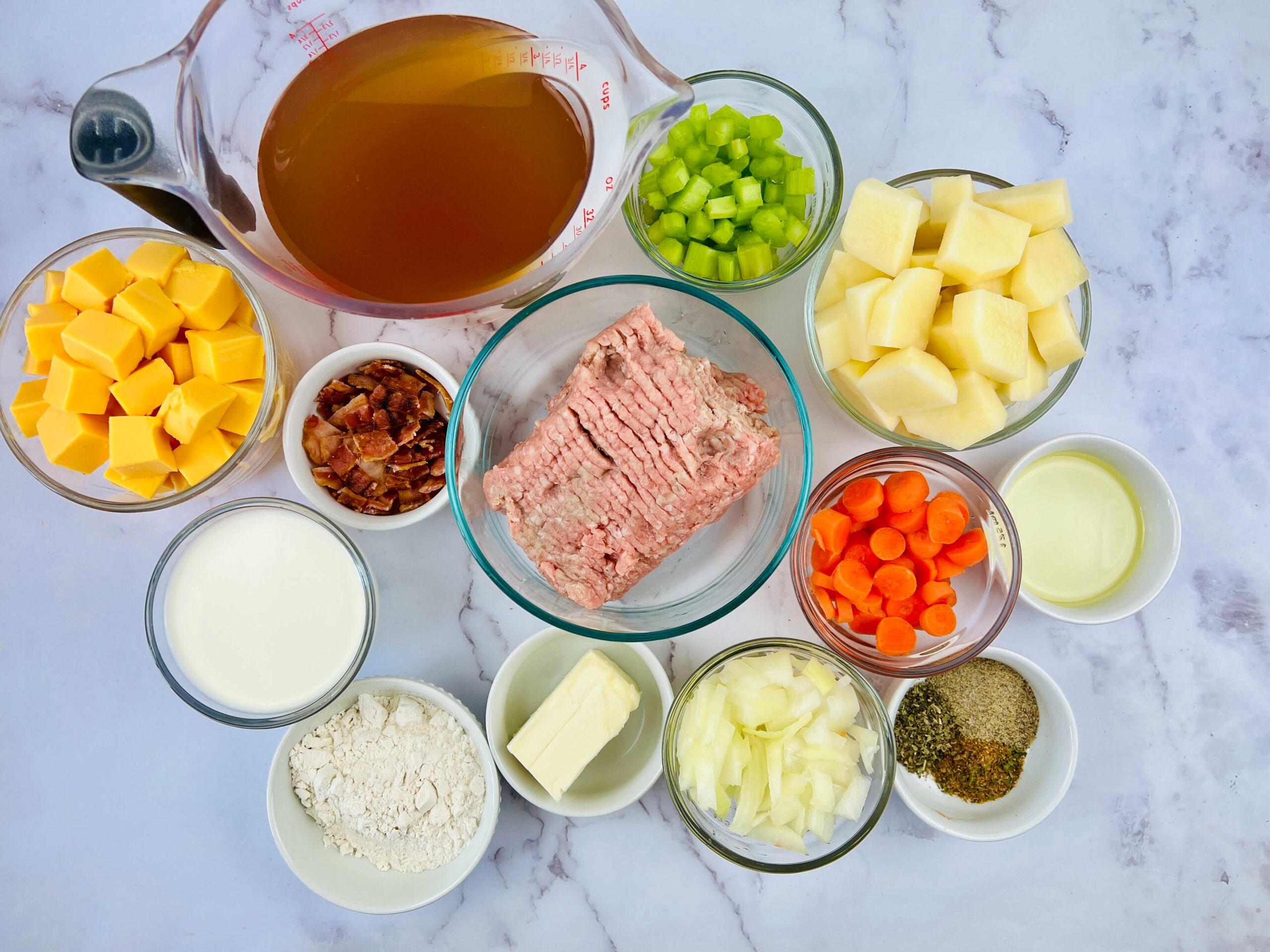 The ingredients for a savory soup. Ground beef, vegetables, broth and seasonings.