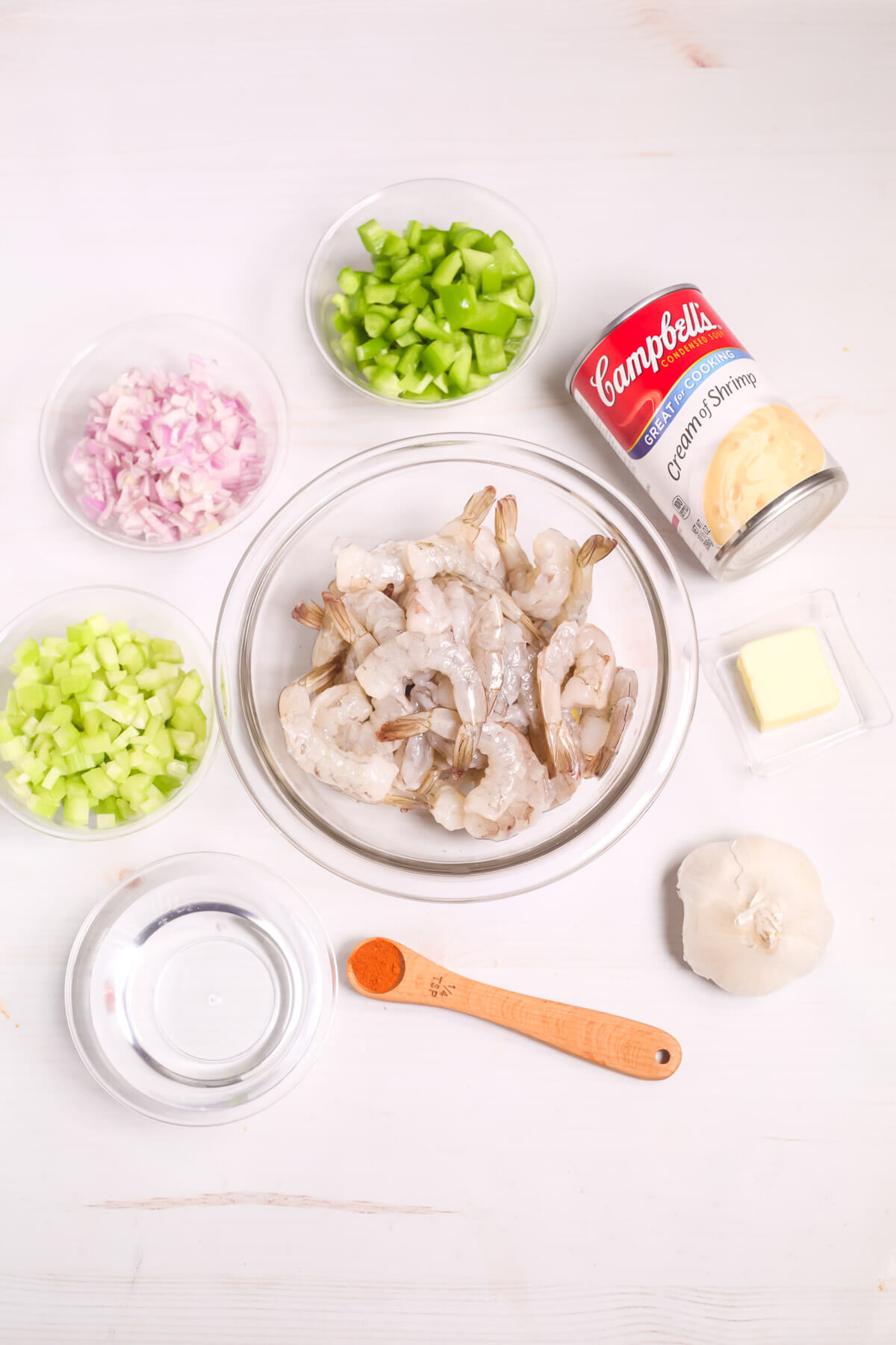 Ingredients laid out for a Creamy Garlic Shrimp and Rice recipe, including shrimp, diced vegetables, garlic, butter, and a can of cream of shrimp soup.