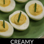 Deviled eggs without mustard garnished with chive served on a green plate.
