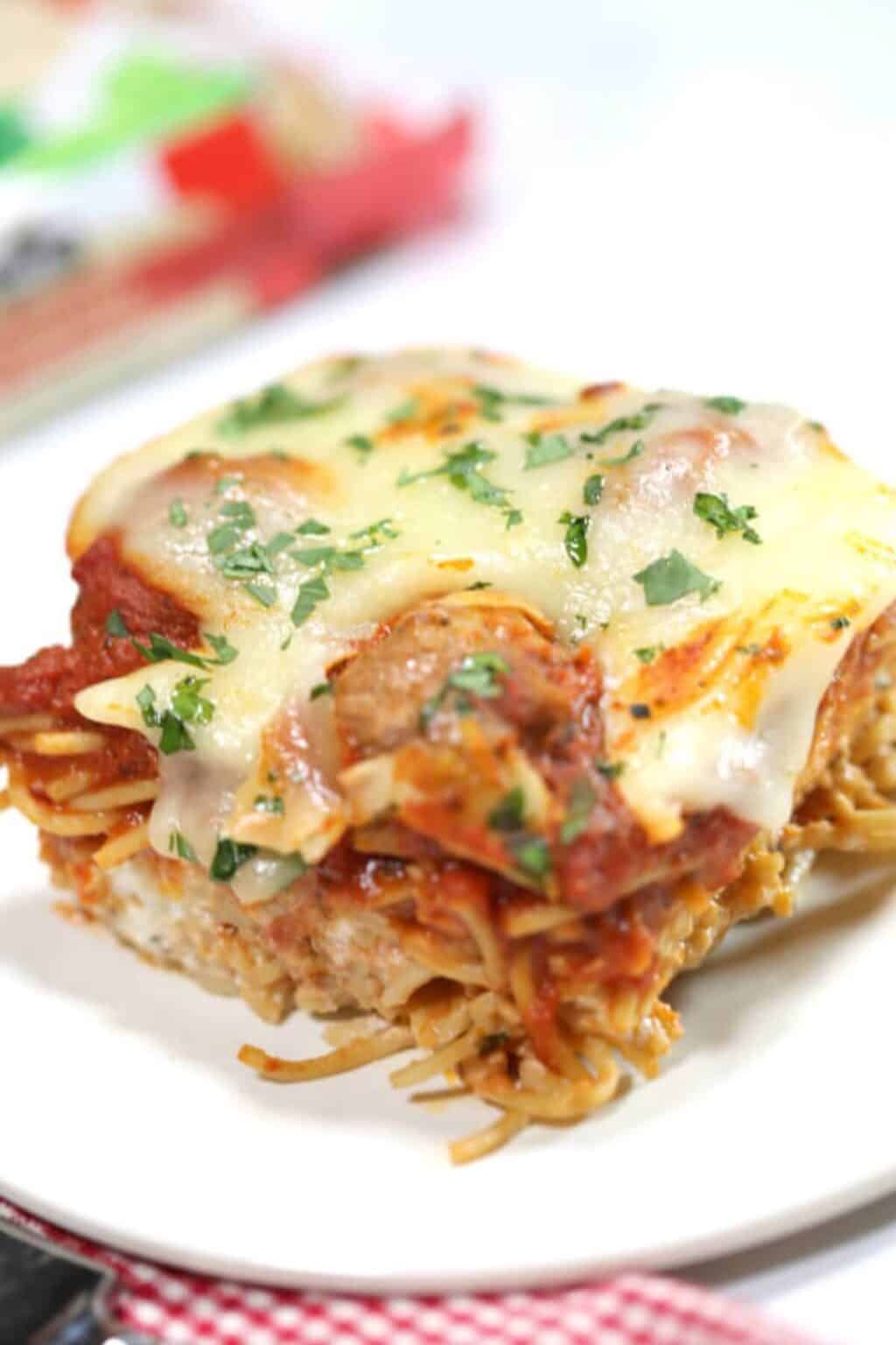 A serving of spaghetti casserole with meatballs on a white plat.