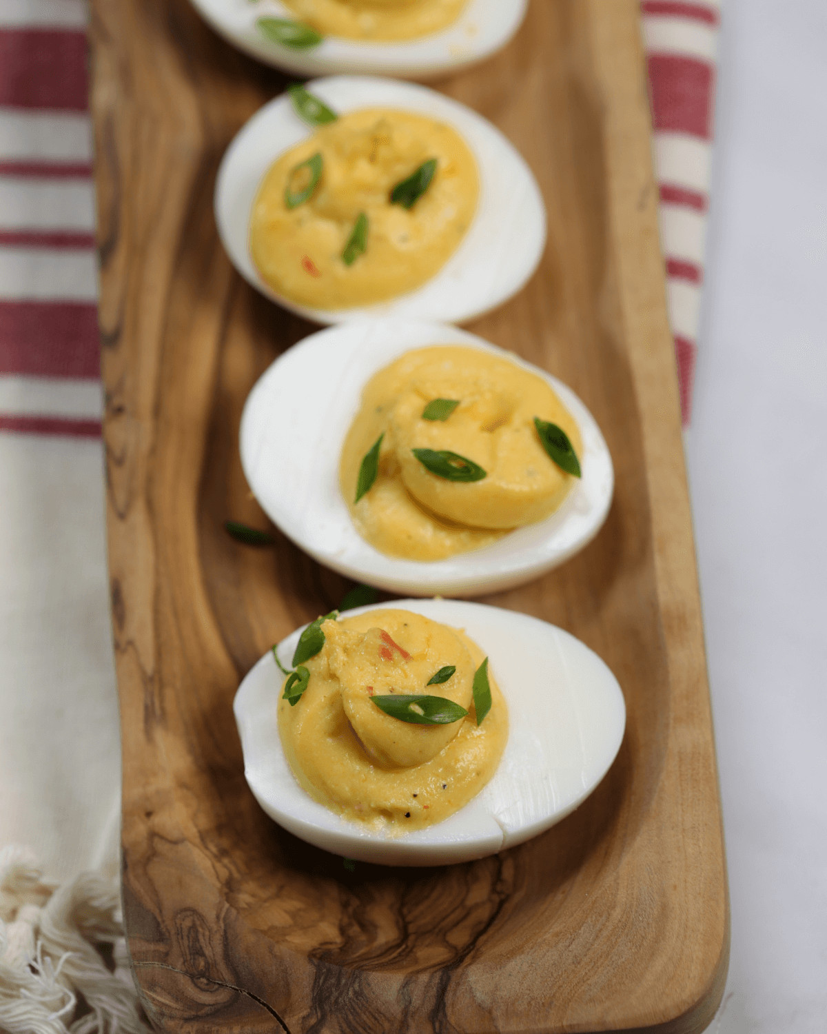 A platter of spicy deviled eggs garnished with paprika and chives.