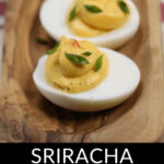 Sriracha spicy deviled eggs on a wooden platter.