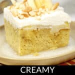A slice of creamy banana cream poke cake topped with whipped cream, fresh banana slices, and crumbled cookies on a plate.