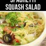 A bowl of California Spaghetti Salad with visible ingredients including black olives, diced tomatoes, chopped broccoli, and various greens. The bowl is set on a wooden surface. The label reads "California Spaghetti Squash Salad.