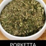 A white bowl filled with Porketta Seasoning, a savory blend of dried herbs and spices, sits on a wooden surface.
