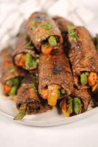 A white platter of balsamic steak roll ups.