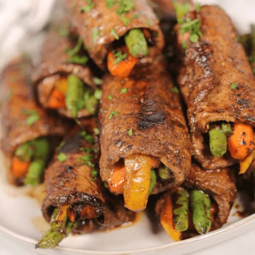 A white platter of balsamic steak roll ups.