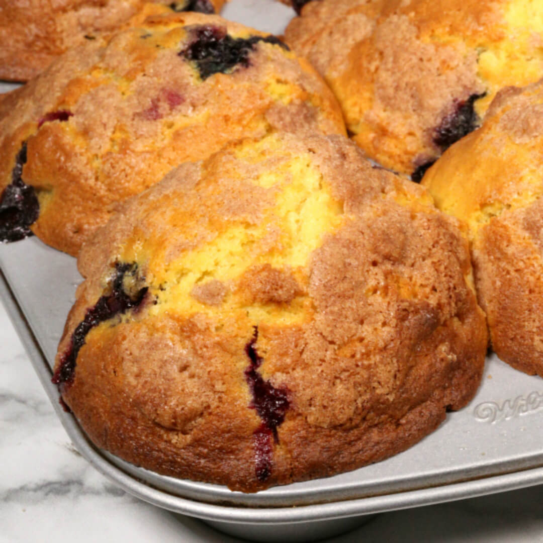 blueberry streusel muffins in a gray muffin pan.