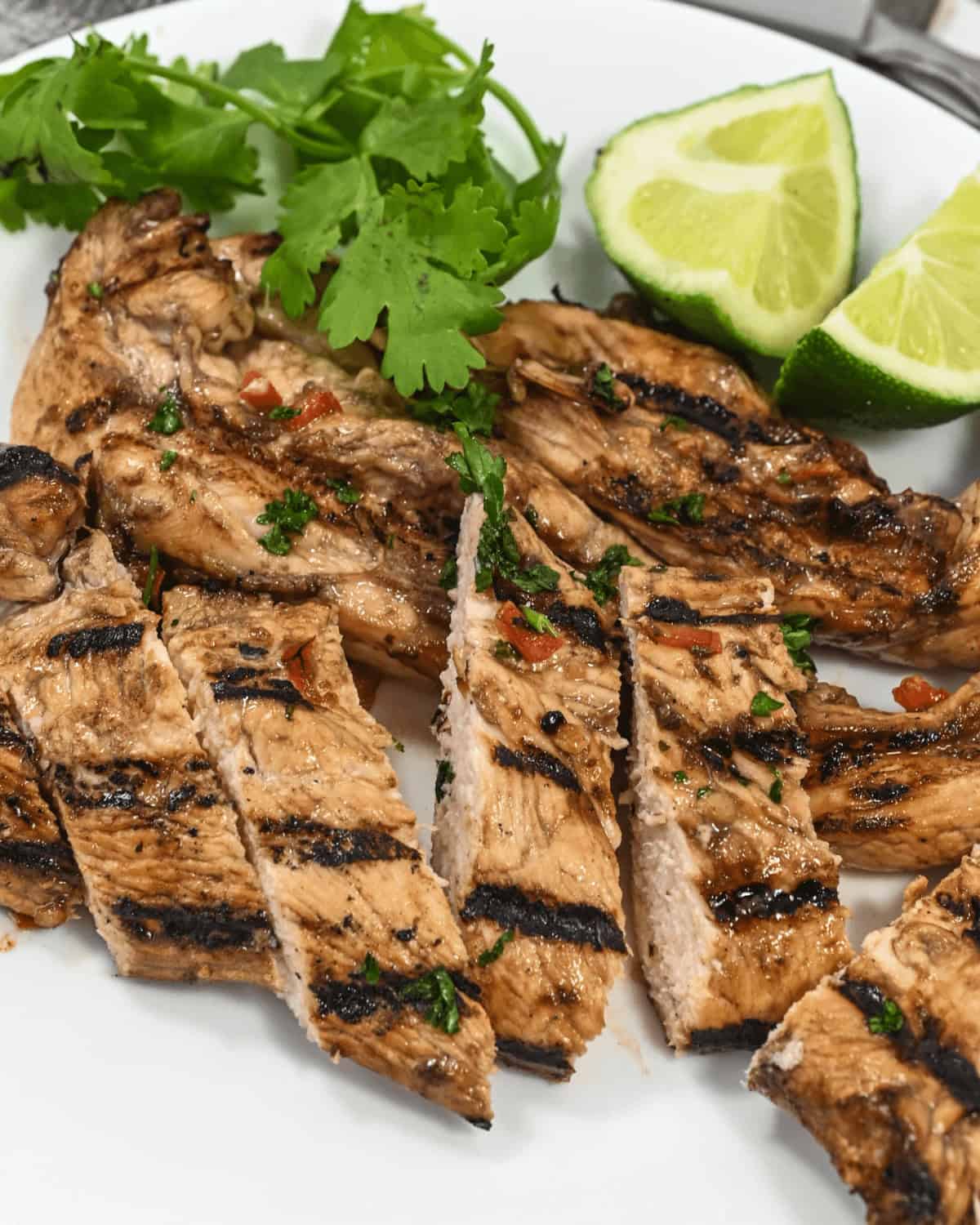Sliced and served with lime wedges and parsley on a white plate.