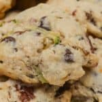 A close-up of chunky zucchini cookies with visible chocolate chips and green pieces, stacked on a white plate.