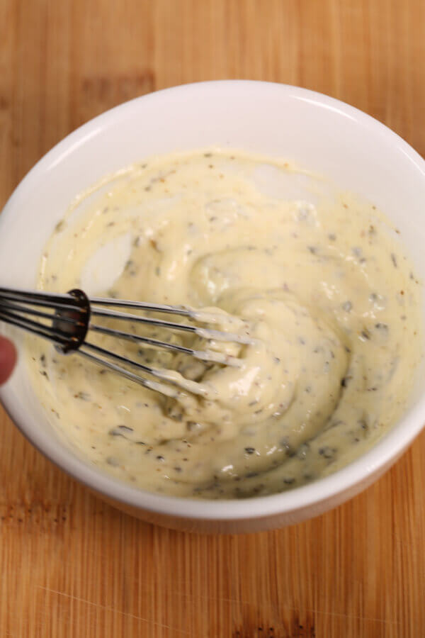 Creamy Italian Dipping Sauce with whisk in white bowl.