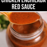 A spoon drizzling Chicken Enchilada Red Sauce into a glass jar, with a backdrop of fresh herbs.