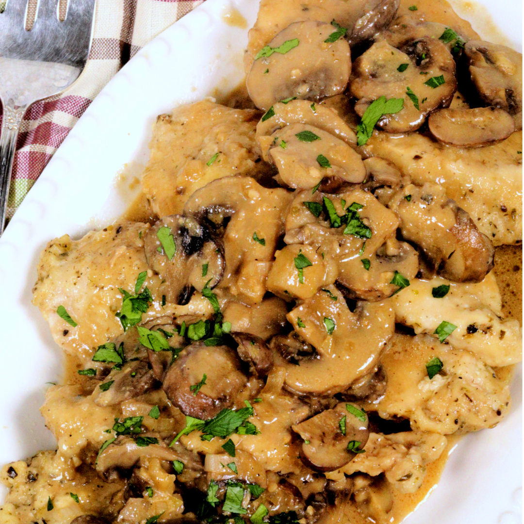 Instant Pot Chicken Marsala with mushrooms on a white platter with a plaid napkin