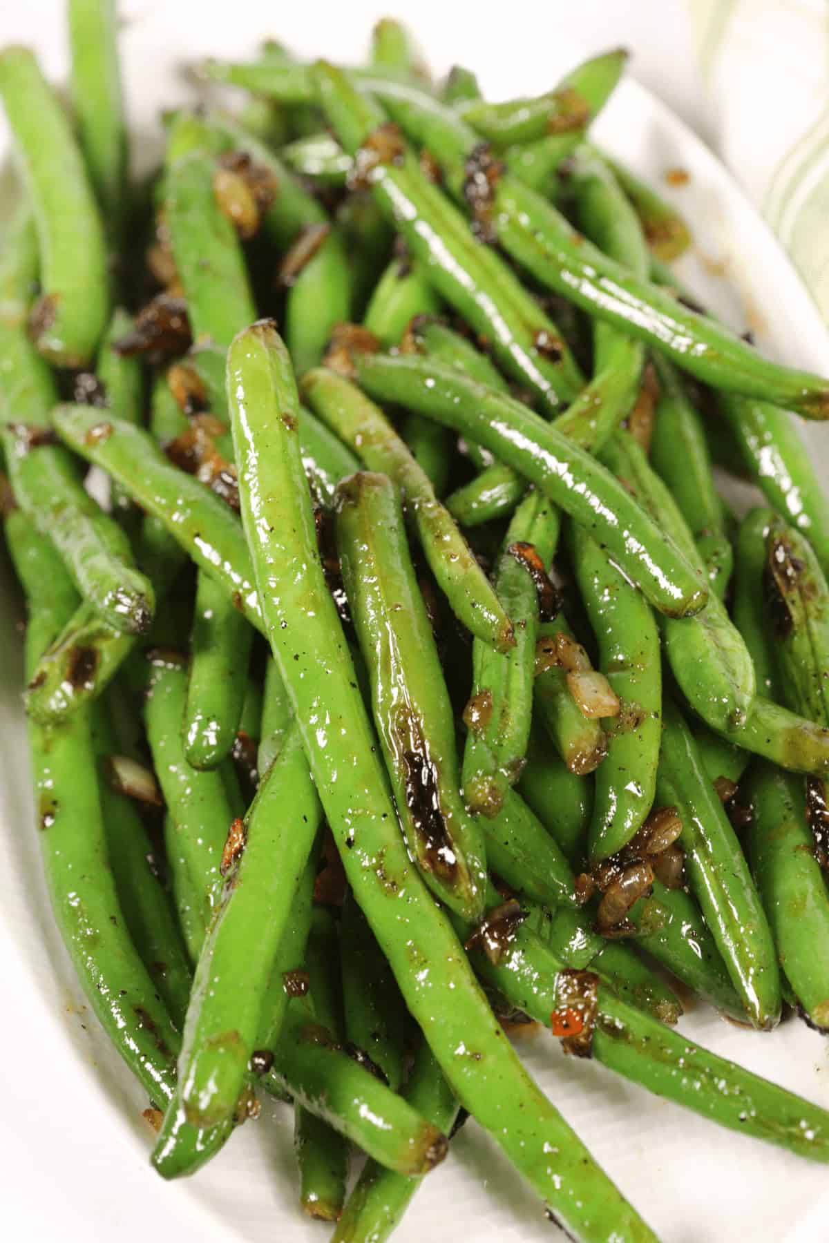 A plate of spicy sautéed green beans with caramelized onions and seasoning.