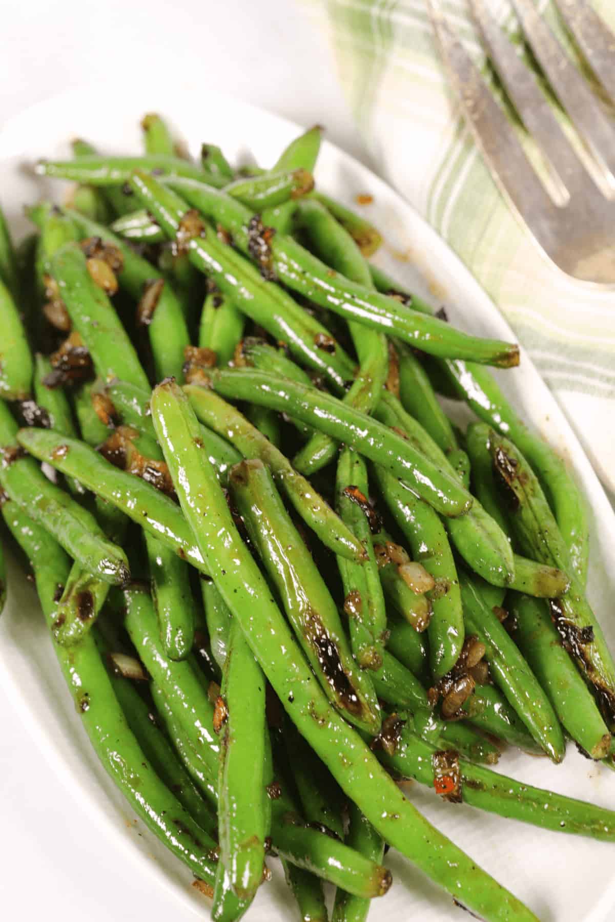 A plate of spicy green beans tossed with chopped onions.