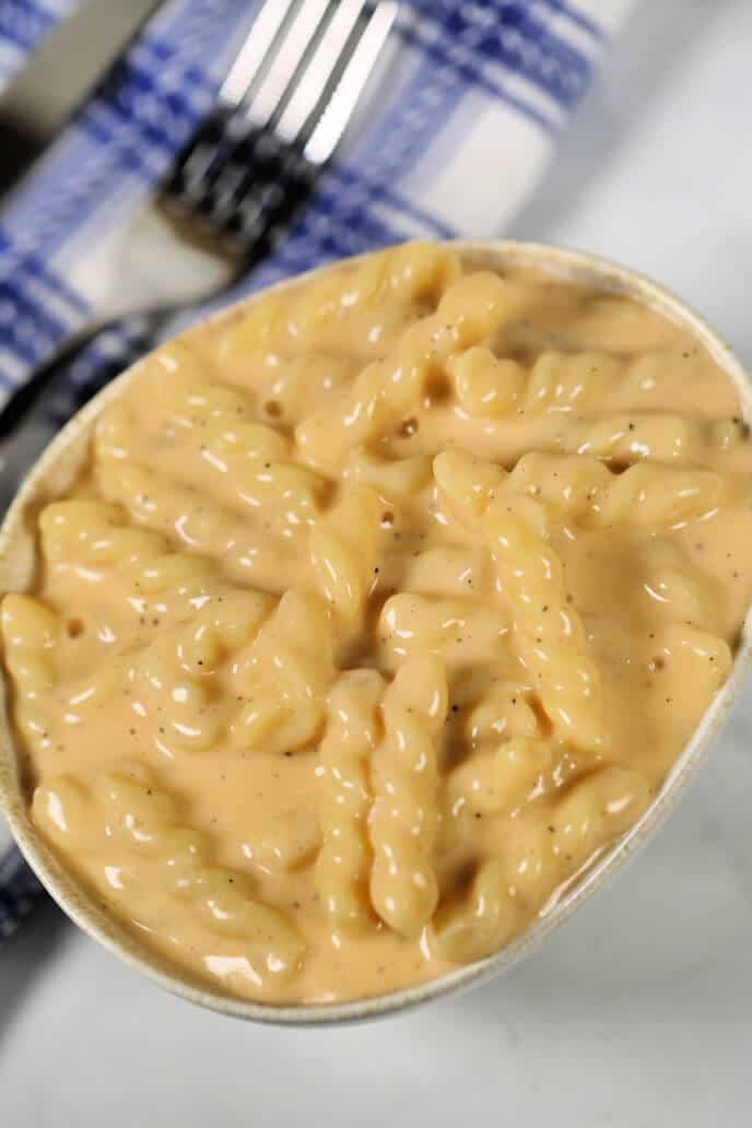 Macaroni and cheese in a small bowl with a blue plaid napkin and fork