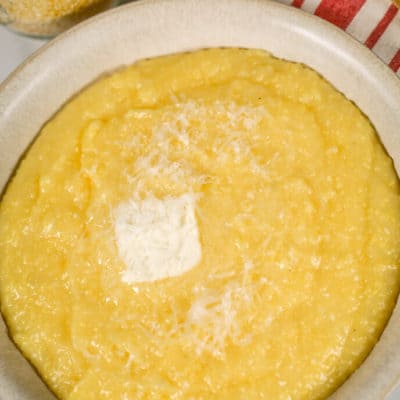 Creamy polenta in a bowl with a striped napkin and wooden spoon