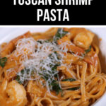 A bowl of Tuscan shrimp pasta topped with grated cheese.