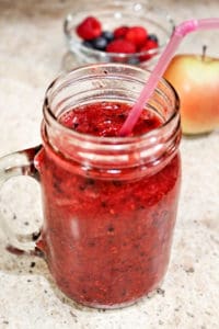 Berry smoothie in a mason jar with pink straw