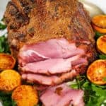 Honey baked ham recipe on a platter with greens and oranges