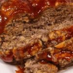 Close-up of an Instant Pot meatloaf topped with a thick layer of barbecue sauce, displayed on a white plate.
