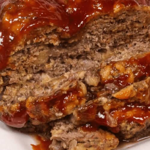Close-up of an Instant Pot meatloaf topped with a thick layer of barbecue sauce, displayed on a white plate.