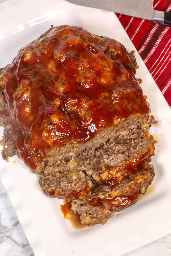 Instant Pot Meatloaf on a white platter with a red striped napkin and a steak knife