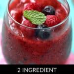 A glass of Mixed Berry Smoothie topped with whole raspberries, blueberries, and a mint leaf, with text at the bottom reading "2 Ingredient Mixed Berry Smoothie.