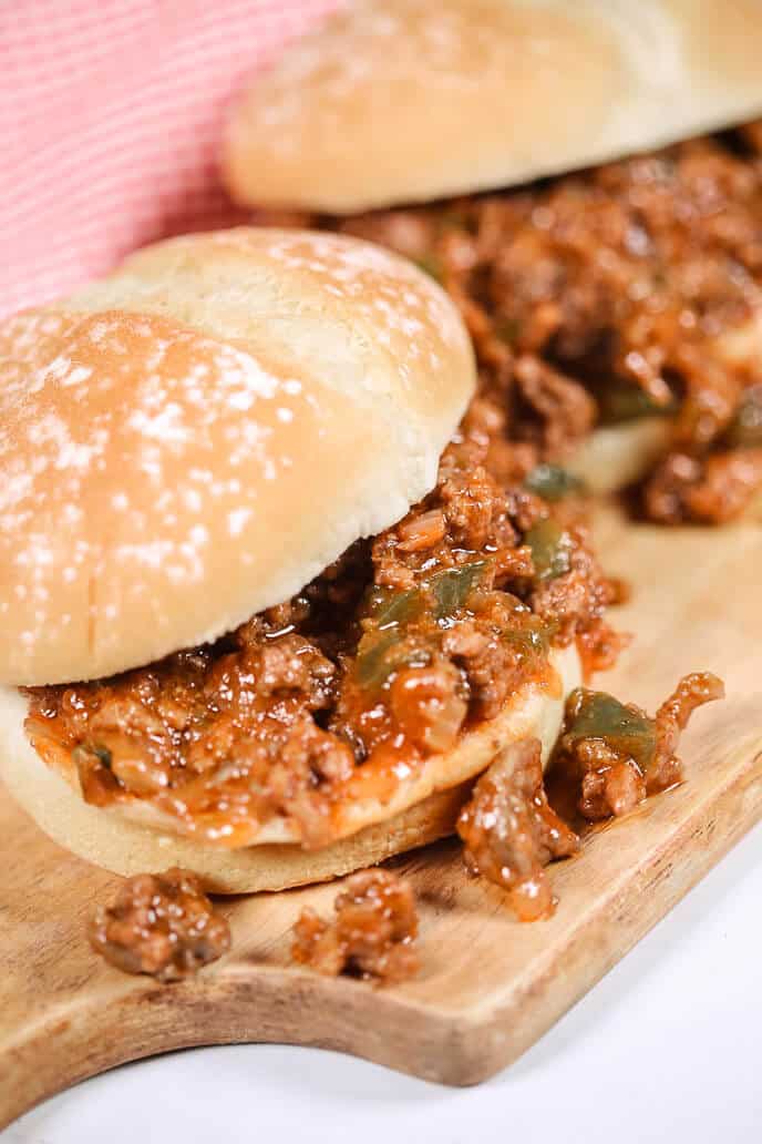 sloppy joes on a wooden board with a checkered napkin