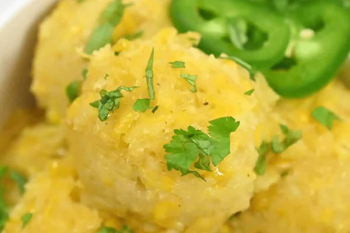 Close-up of a yellow corn cake, perfect for Cinco de Mayo food festivities, topped with chopped cilantro and sliced green jalapeños.