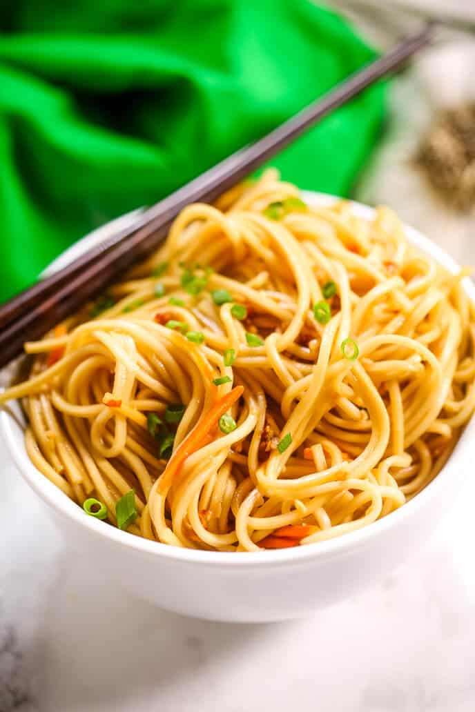 Easy sesame noodles in a white bowl with chopsticks and a green napkin