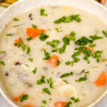 A bowl of Creamy Chicken Wild Rice Soup with vegetables and herbs.