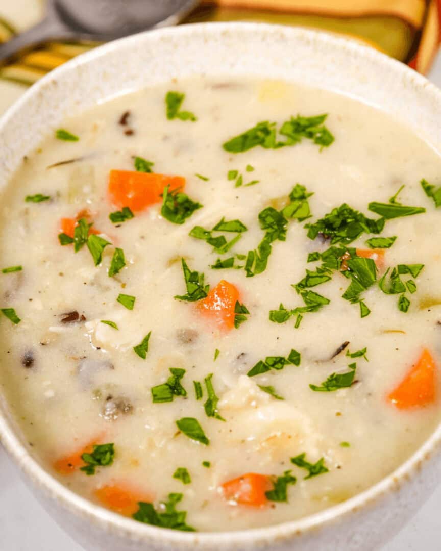 A bowl of Creamy Chicken Wild Rice Soup with vegetables and herbs.