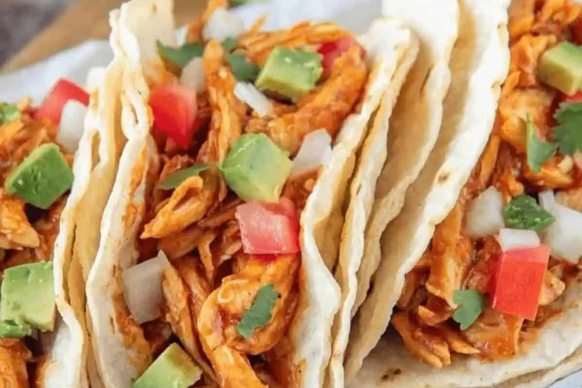 Tacos packed with shredded chicken, avocado chunks, diced tomatoes, onions, and cilantro in soft tortillas make the perfect Cinco de Mayo food.