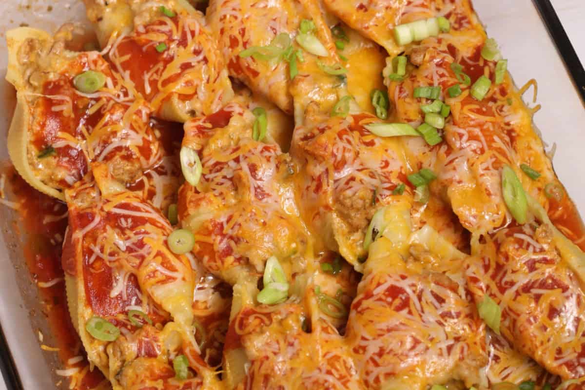 Stuffed pasta shells topped with melted cheese and sliced green onions in a baking dish, perfect for adding a festive touch to your Cinco de Mayo food lineup.