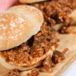 Two delicious Wimpies, also known as Easy Sloppy Joes, filled with a savory mixture of ground meat, onions, and green peppers on a wooden board.