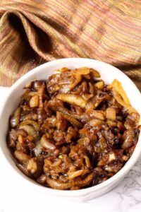 Caramelized onions in a white dish with tan napkin