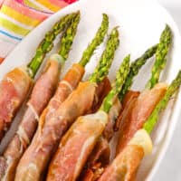 Prosciutto Asparagus on a white plate with a colored napkin