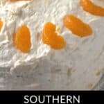 A frosted cake decorated with segments of mandarin oranges on top has "Southern Pig Cake" elegantly written at the bottom.