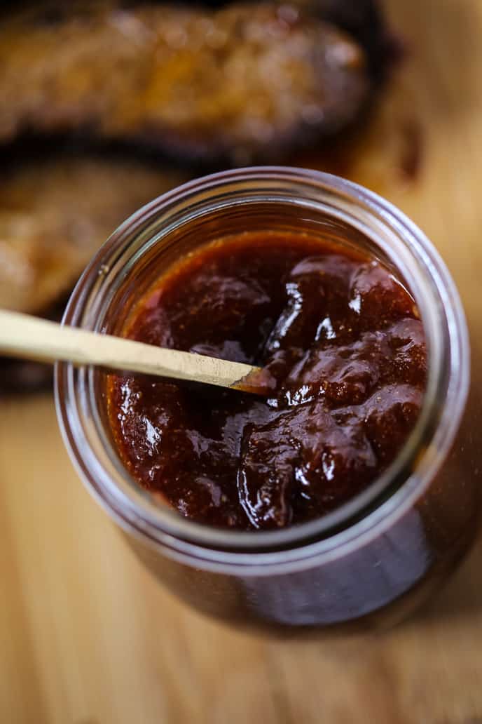 homemade barbecue sauce in a jar with gold spoon