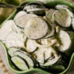 Close-up of a bowl containing a cucumber onion salad with sliced cucumbers, onions, and a creamy dill dressing.