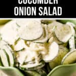 Close-up of a bowl filled with creamy cucumber onion salad, garnished with herbs, placed in a green bowl. The text at the top reads "Creamy Cucumber Onion Salad.
