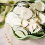 Cucumber salad on pink cake stand in a green scallop bowl