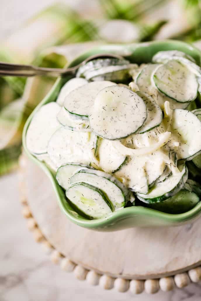 Cucumber salad on pink cake stand in a green scallop bowl