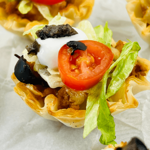 Loaded taco bites with tomatoes, lettuce, and olives.